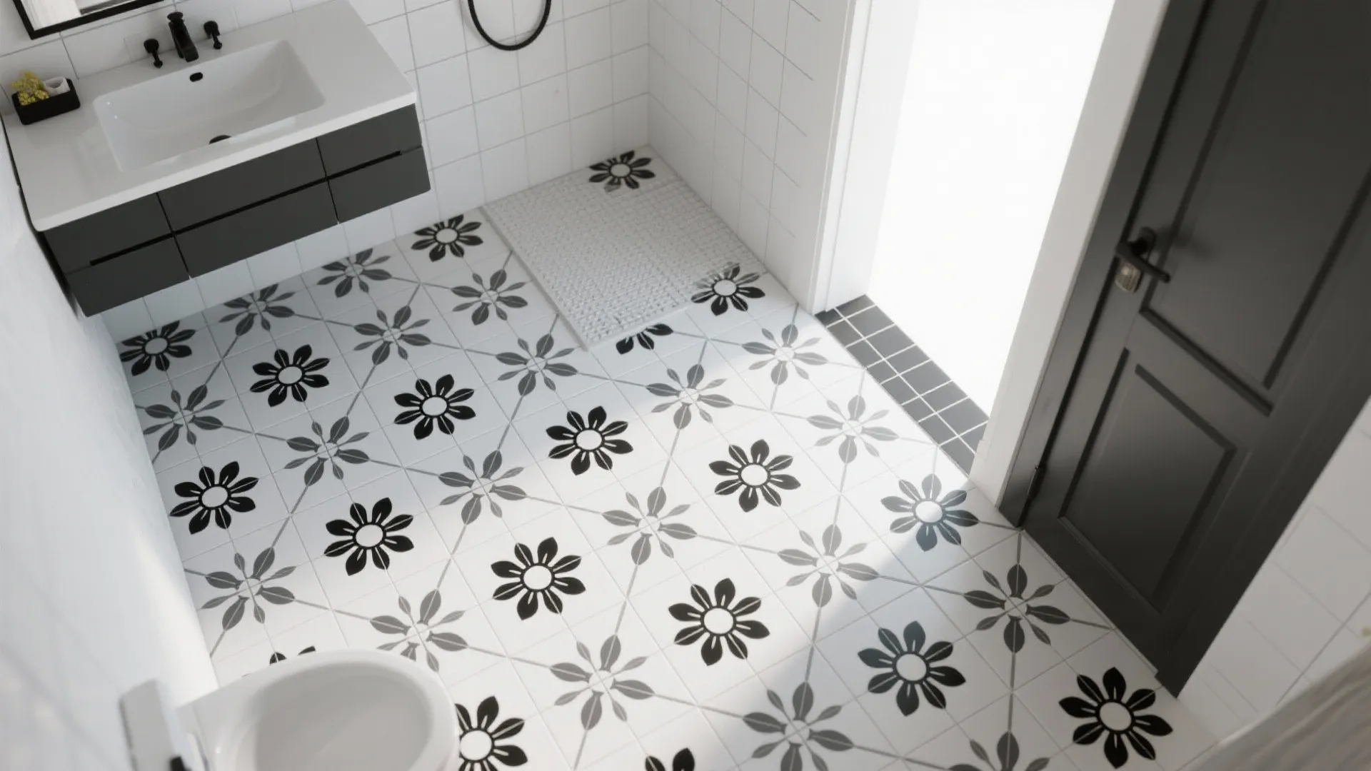 Top-down of black-and-white floral floor tiles with medium-gray grout in a compact bathroom.