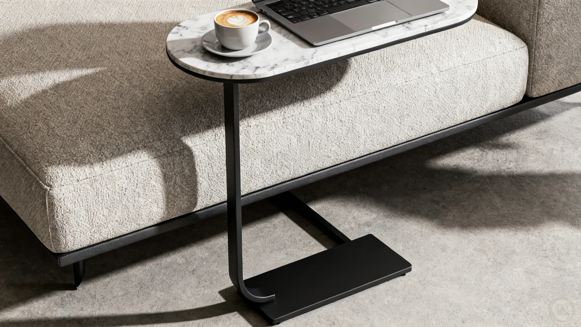 Slim C-shaped metal table slid under a sofa with a marble top holding a coffee cup and laptop.