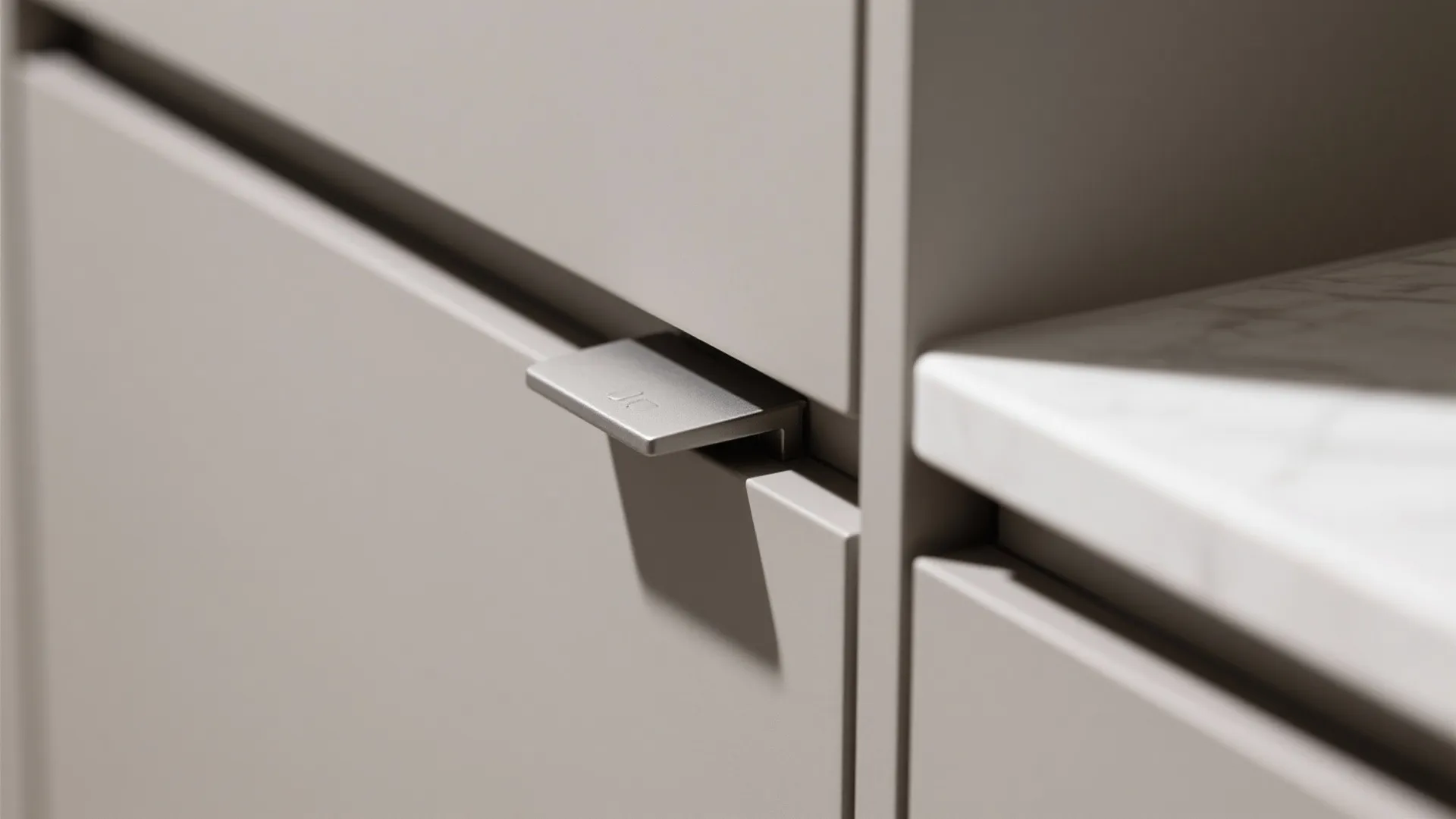 Close up of a modern grey kitchen cabinet with a silver metal finger pull handle