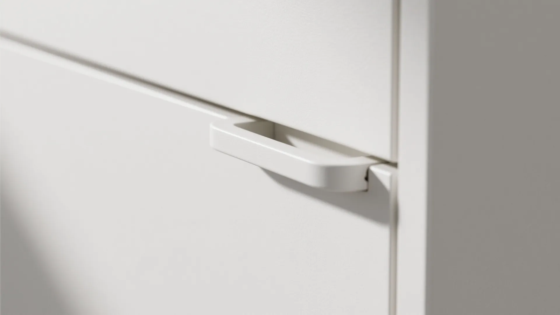 Close up of a white cabinet handle with minimalist design for a modern kitchen storage unit