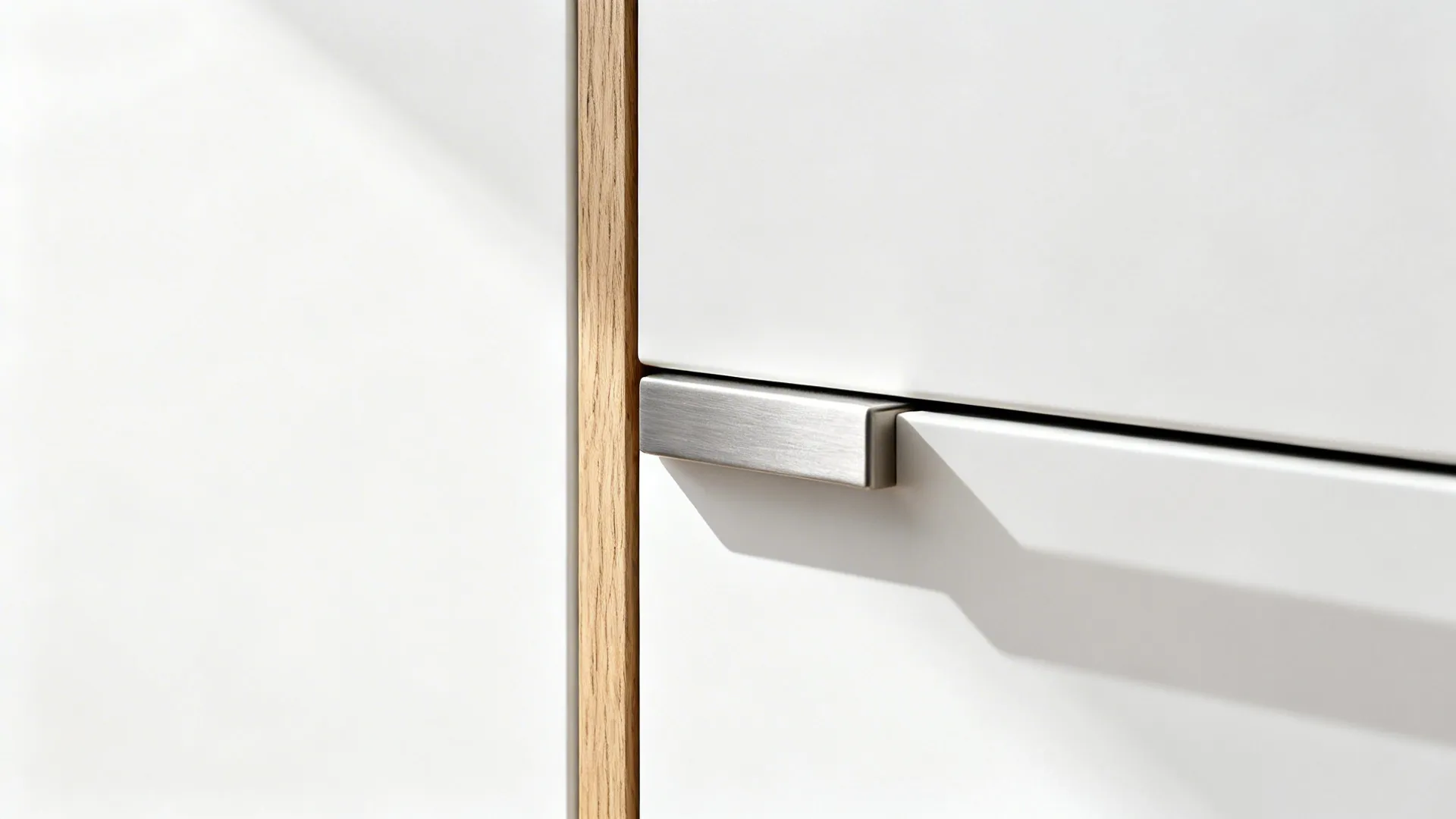 Macro of matte white flat-panel cabinet with slim pull and rift oak edge in soft daylight.