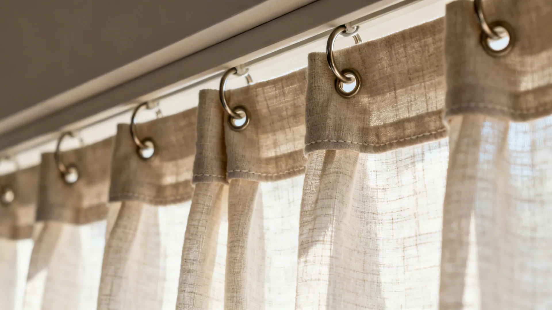 Macro of cotton-linen café curtain on clip rings with tailored pleats and fine weave.