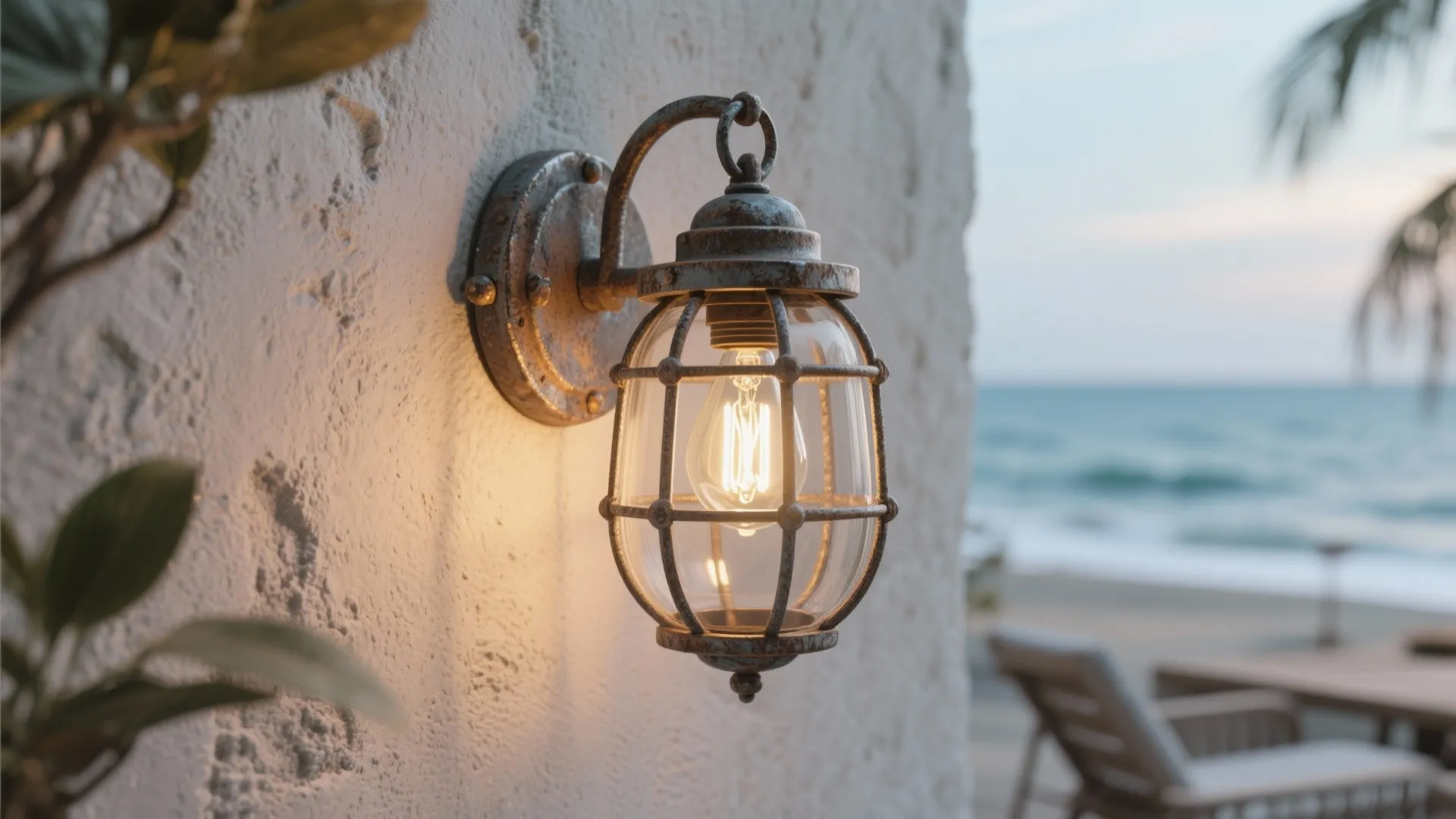 Industrial cage style wall light with warm bulb on white wall with blurry beach background