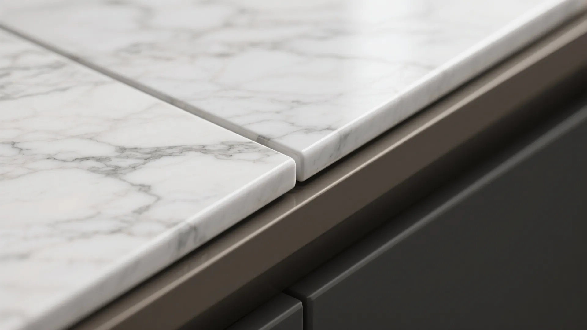 Close up of white marble kitchen countertop with grey veins meeting dark brown cabinet edge