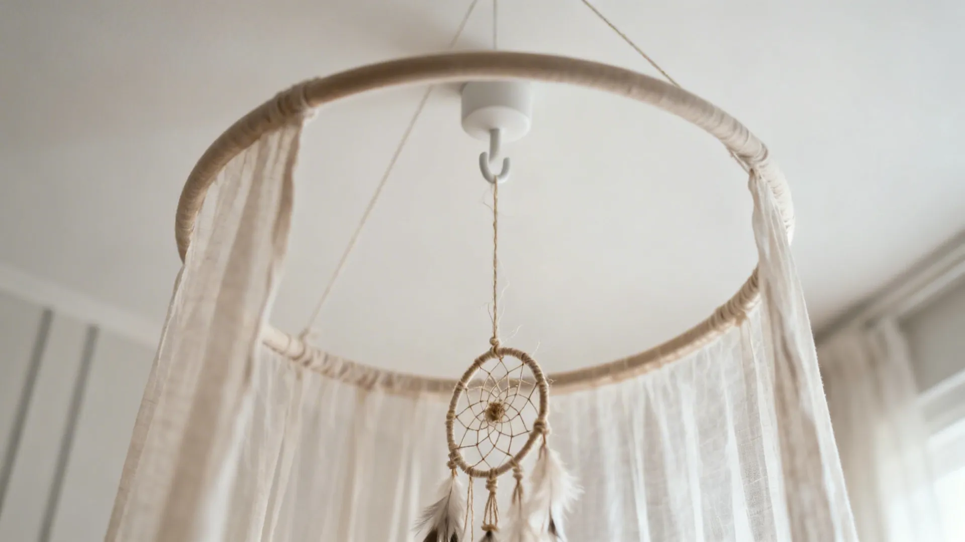 Close-up of a sheer canopy ring with a small dream catcher suspended inside, softly lit.
