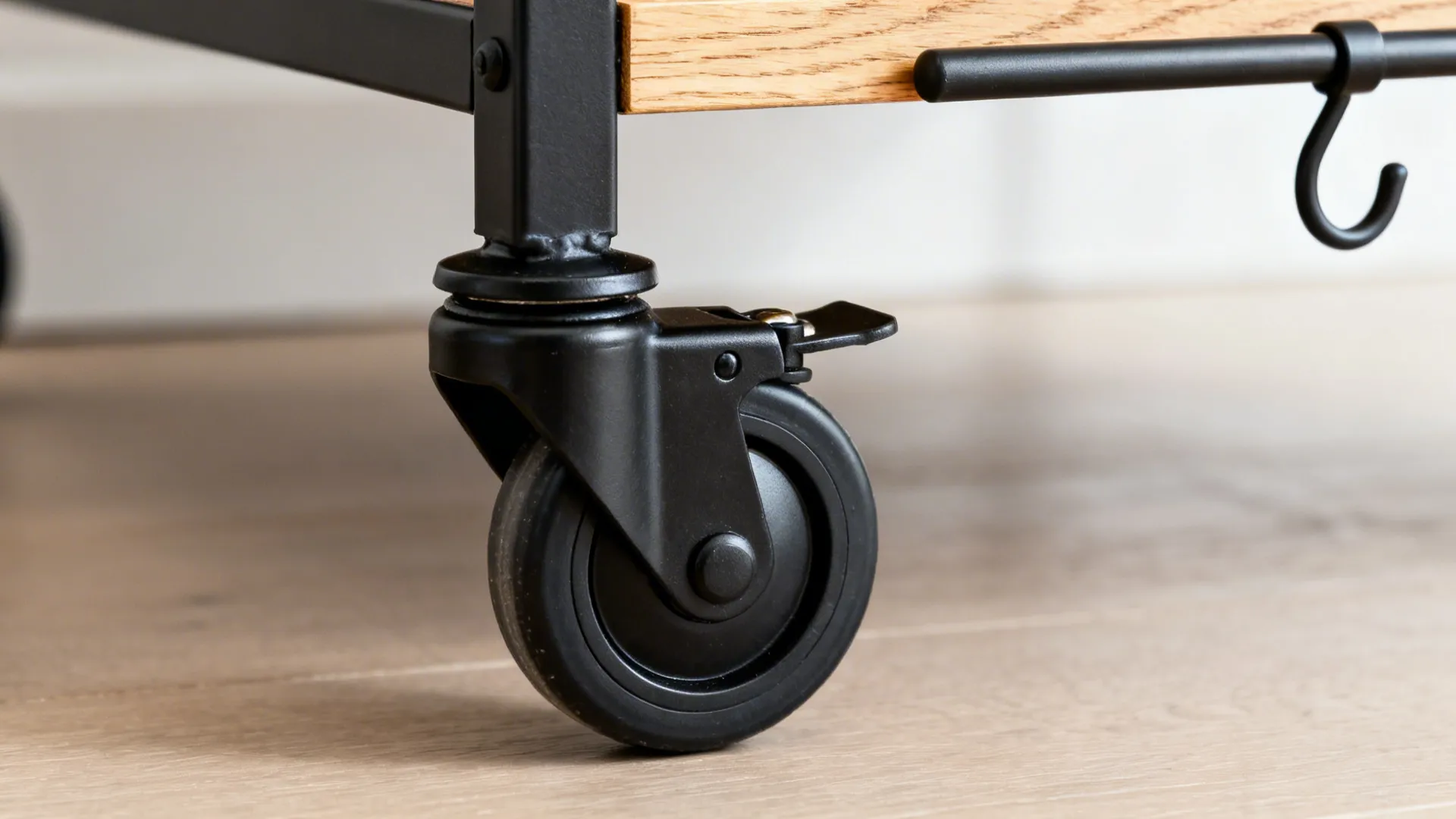 Close up of a black locking wheel attached to a wooden shelf on a light floor