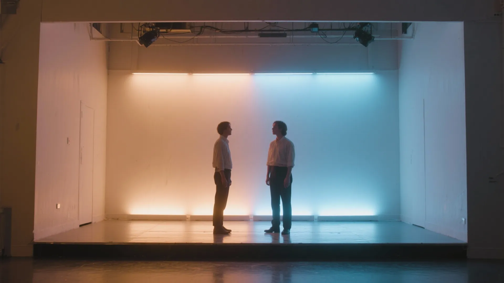 Two people standing on a stage with warm orange and cool blue light wall background