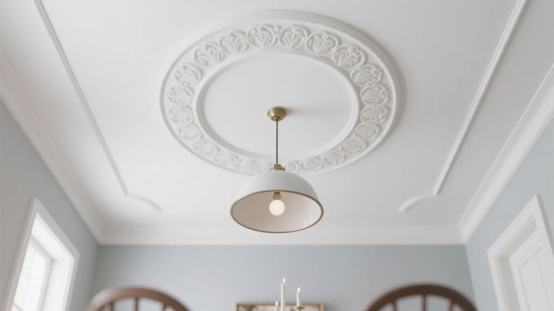 Modern white ceiling light hanging from decorative circular pattern on clean white ceiling in room