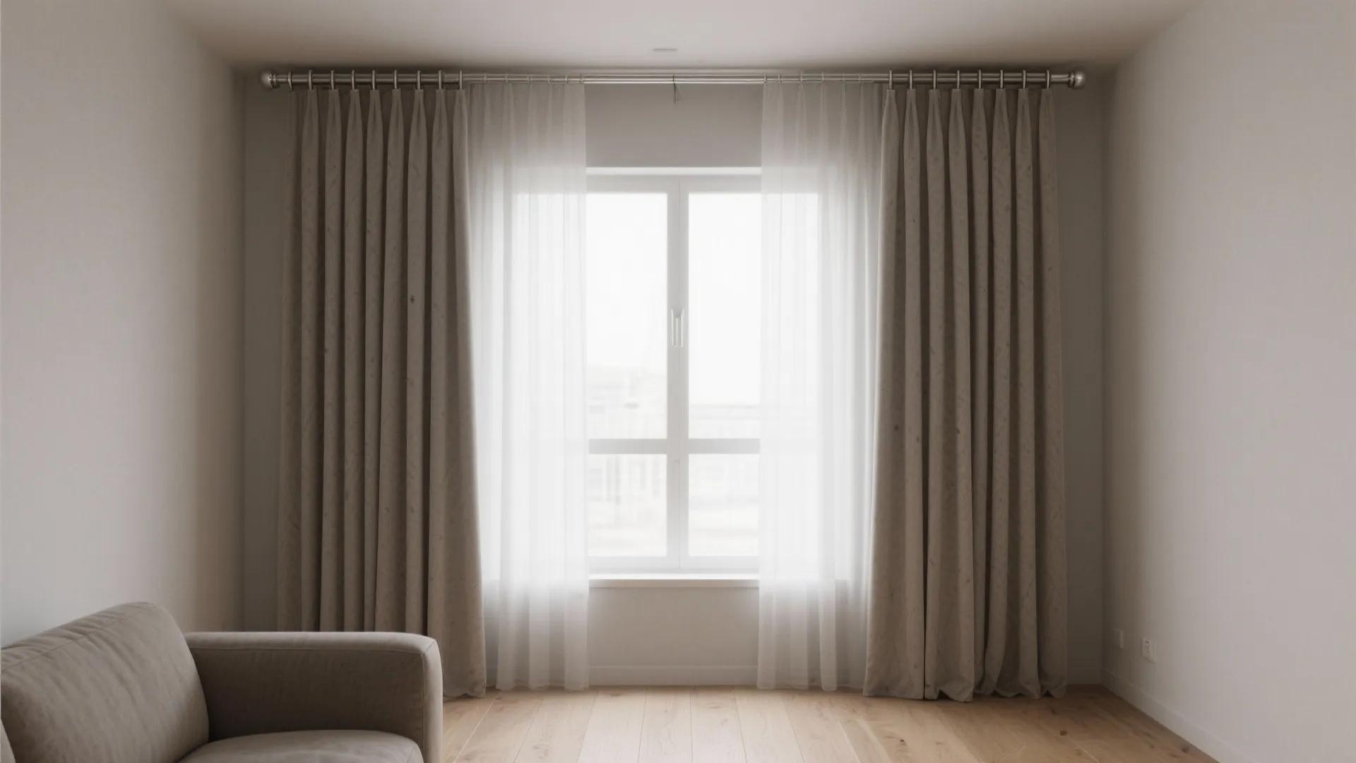 Large window with white sheer curtains and beige hanging drapes over a light wooden floor