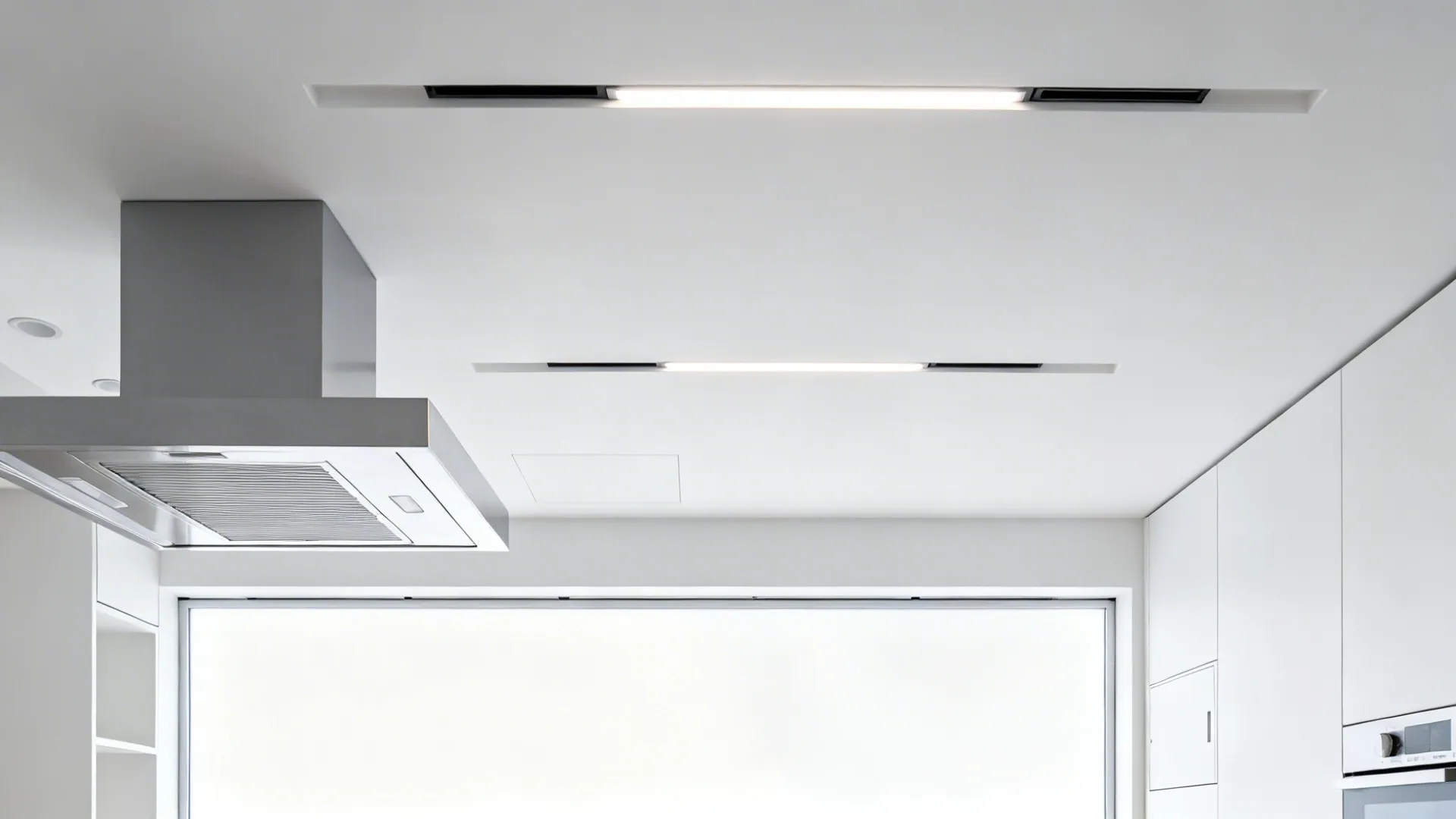 Compact kitchen with shallow ceiling channels guiding light and air toward the hood.