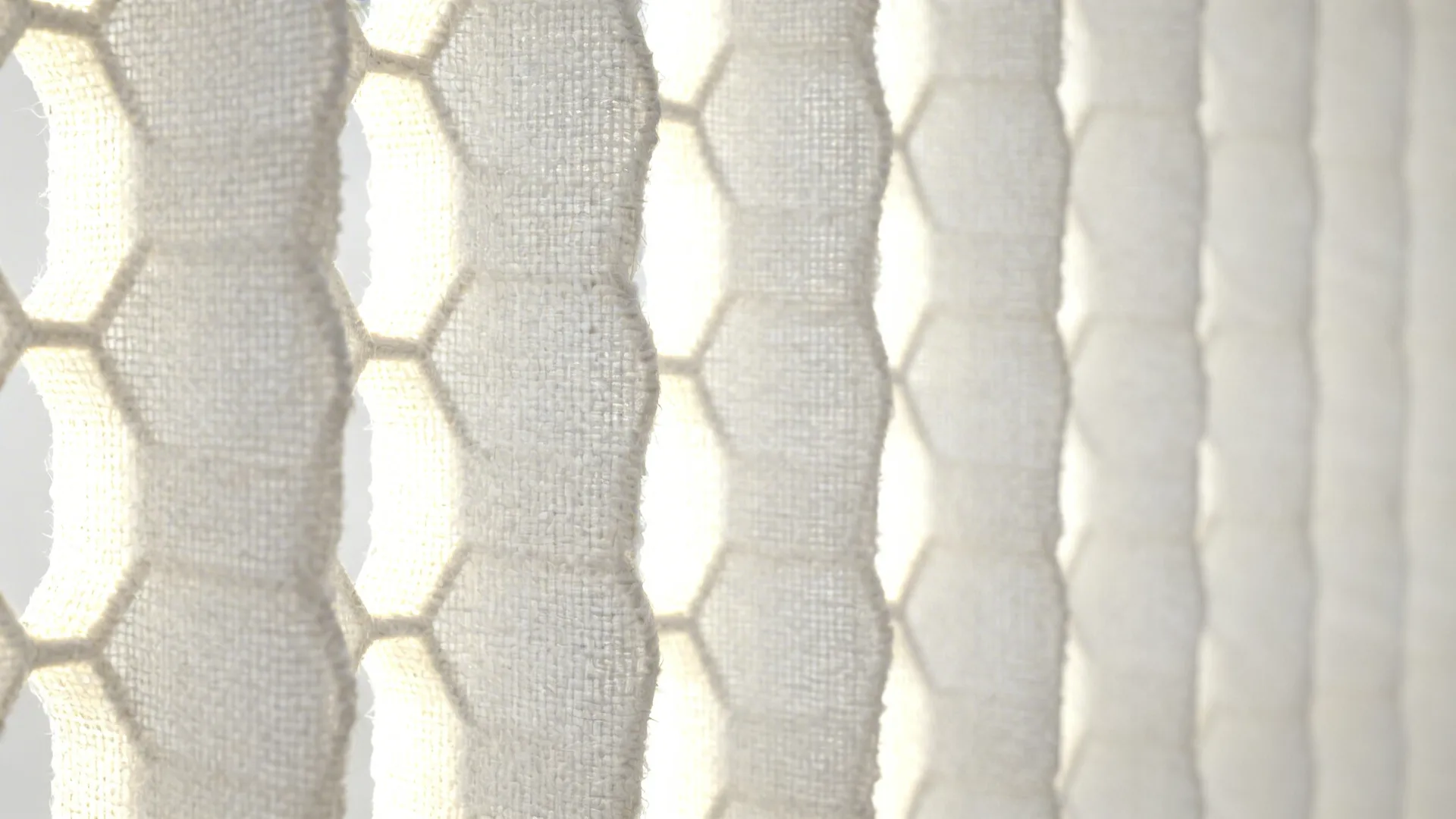 Close up of white honeycomb window blinds showing the fabric texture and bright natural light
