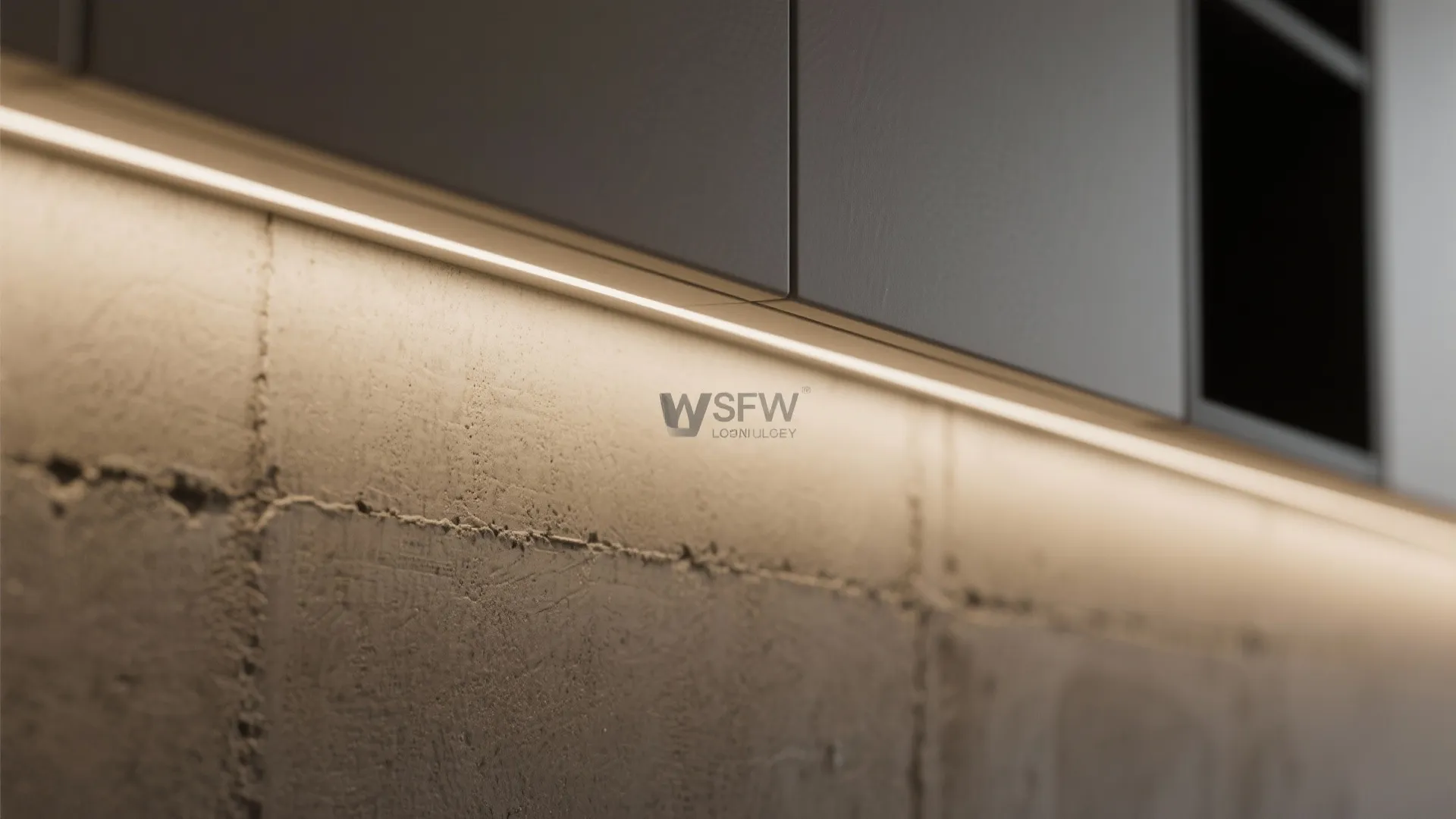 Close up view of a modern grey cabinet with warm strip light against concrete wall