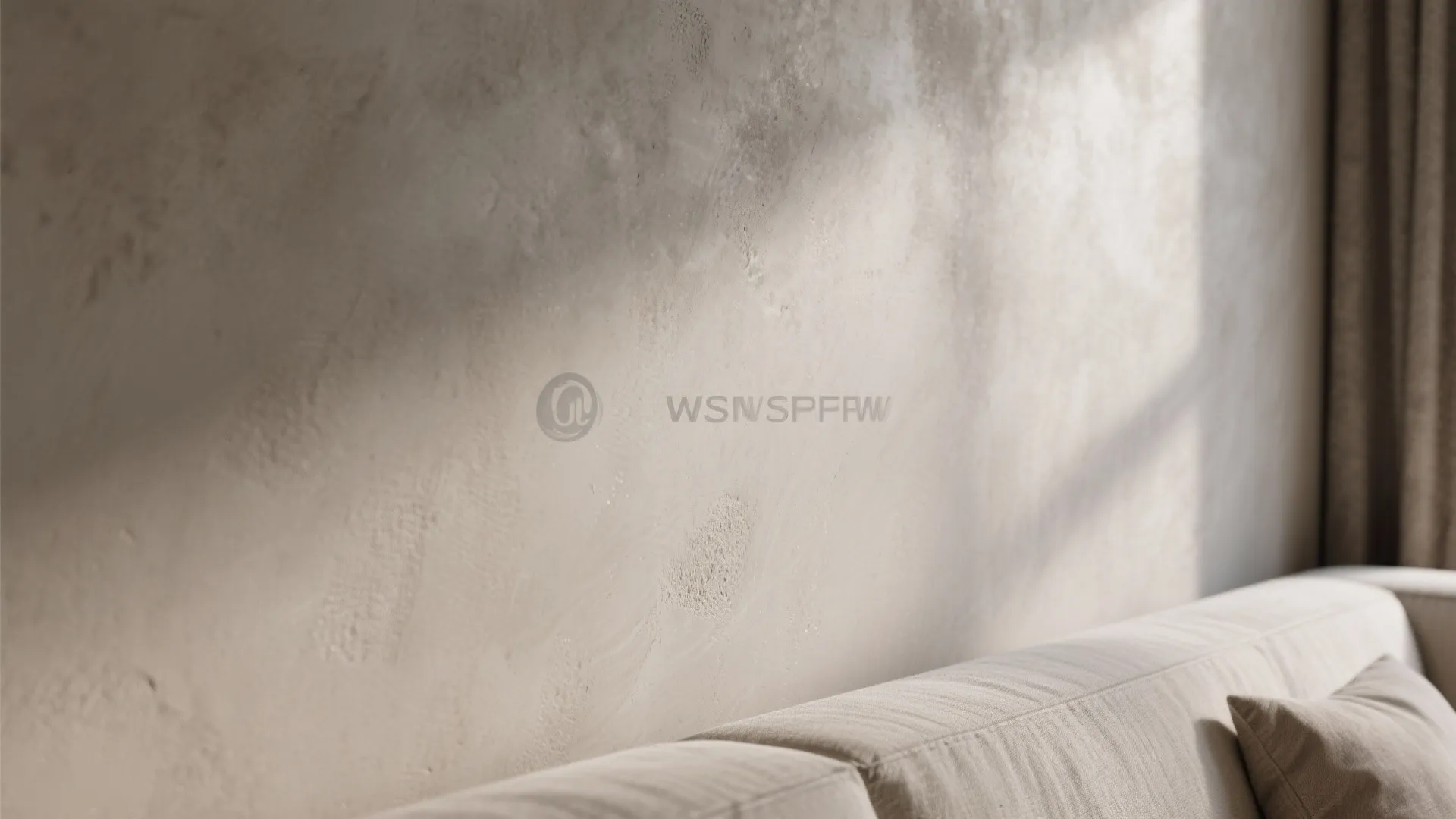 Close up of textured beige plaster wall with sunlight shadows behind a light colored sofa