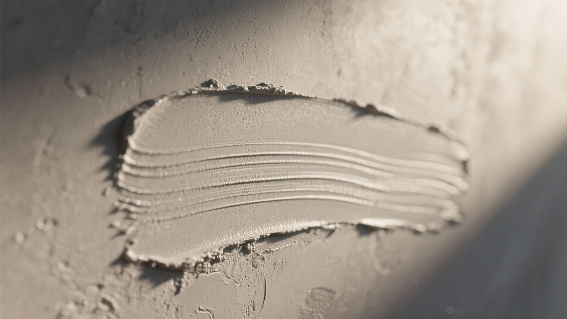 Close up of grey concrete wall texture with a thick brush stroke and natural sunlight
