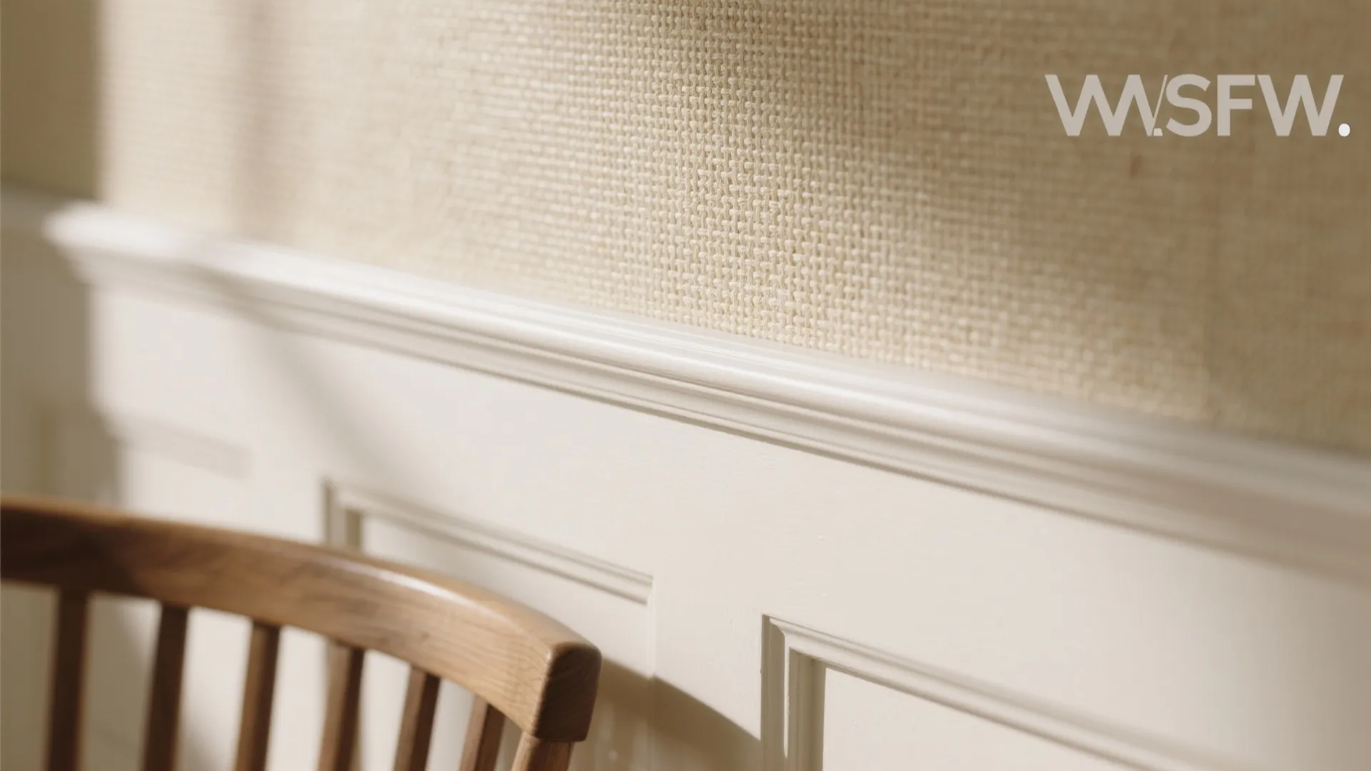 White wall panel detail with a wooden chair and beige textured fabric wall covering design