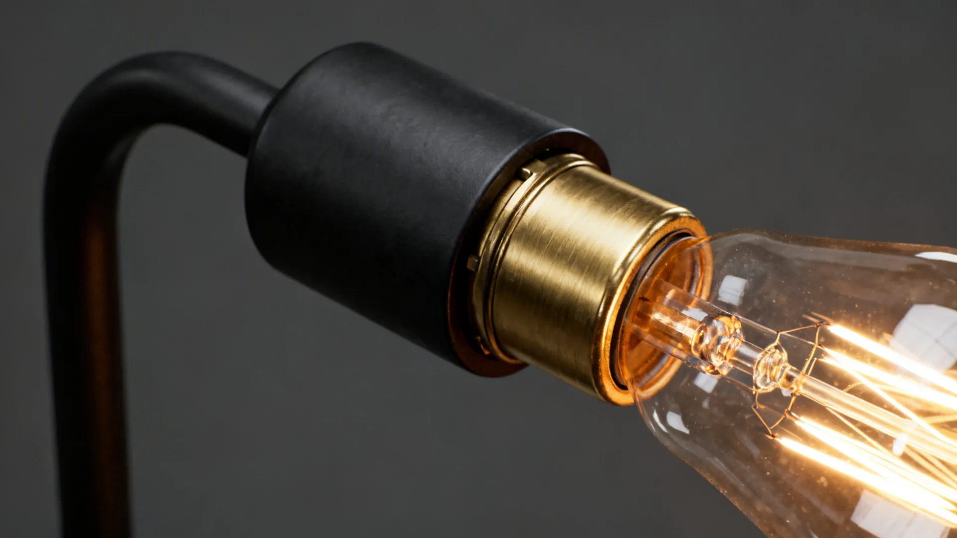 Close-up of matte black arm and brushed gold detail on a chandelier showing finish and bulb warmth.