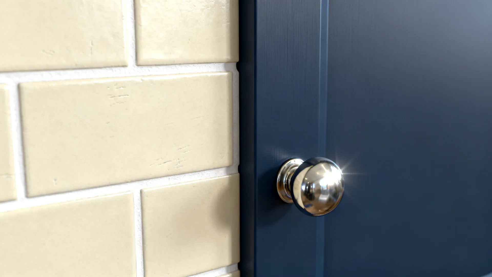 Close up of blue cabinet door with silver knob next to cream colored wall tiles