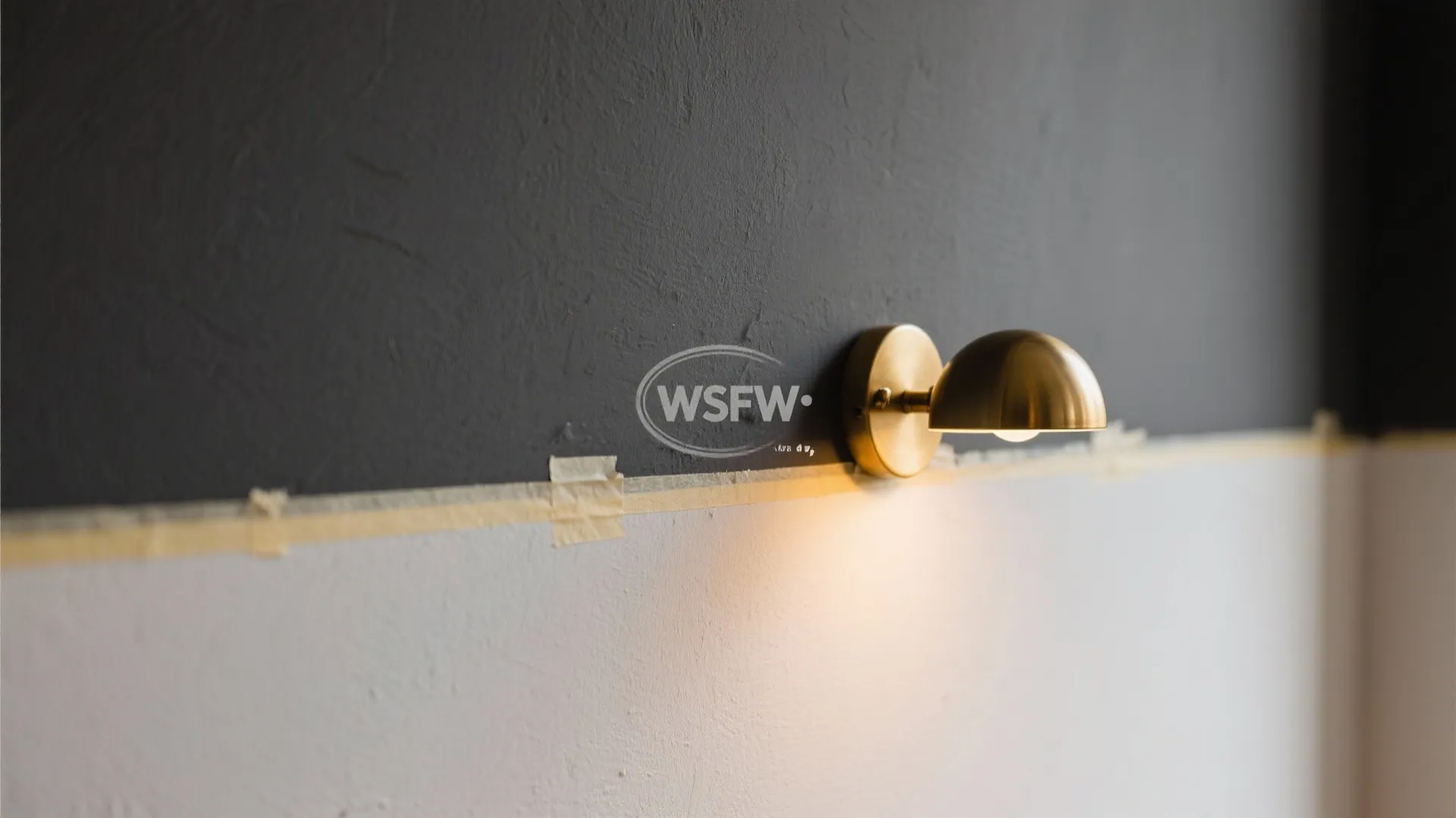 Macro close-up of a charcoal accent wall edge with crisp paint line and warm light from a brass sconce.