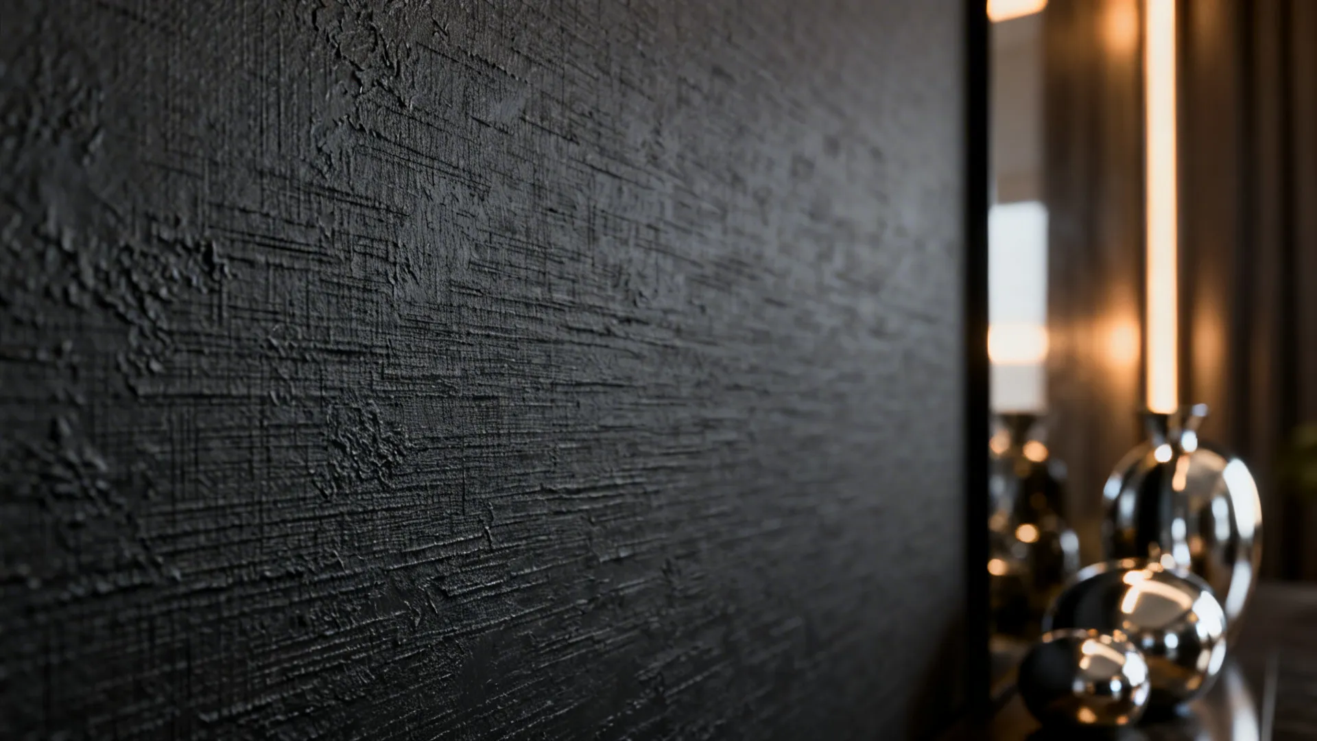 Macro shot of a textured charcoal accent wall showing plaster or grasscloth detail and layered lighting.