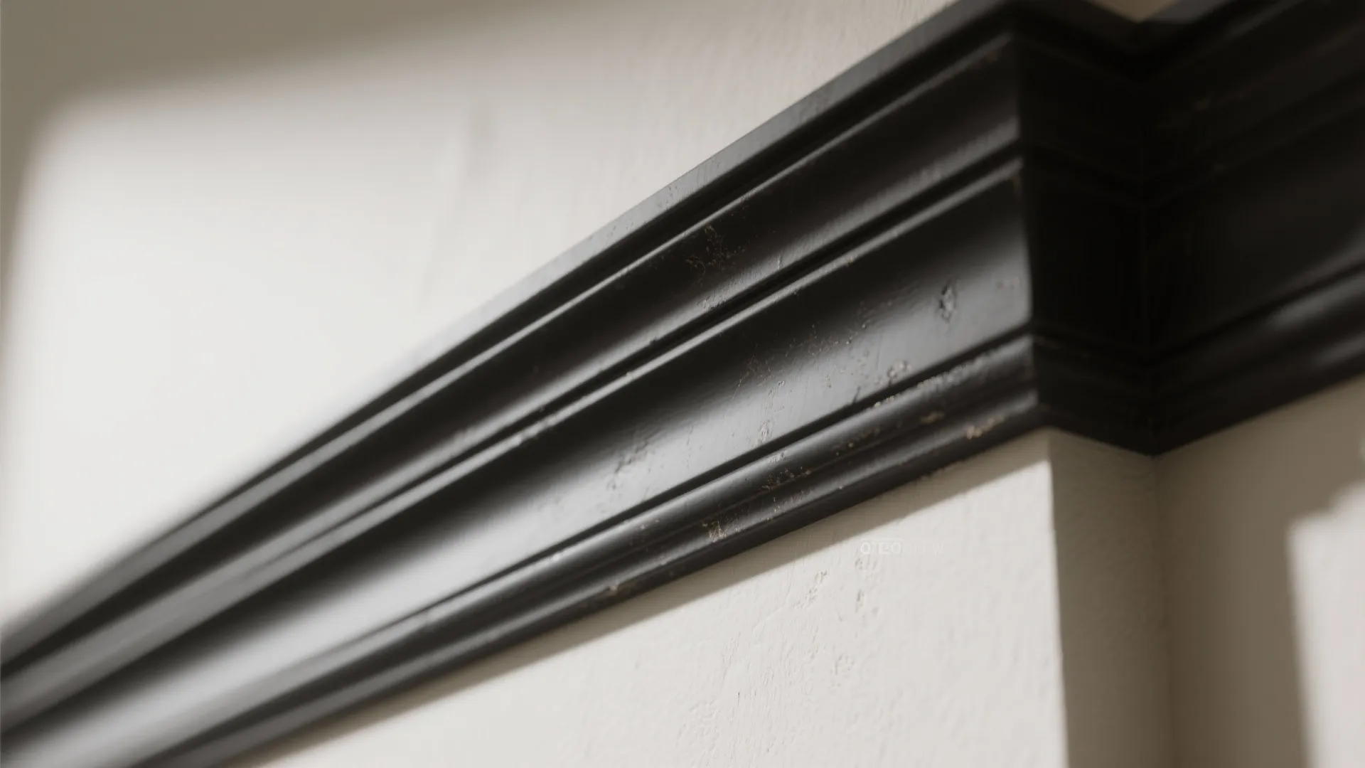 Close-up of deep charcoal trim with semi-gloss finish against a light wall, showing molding detail.