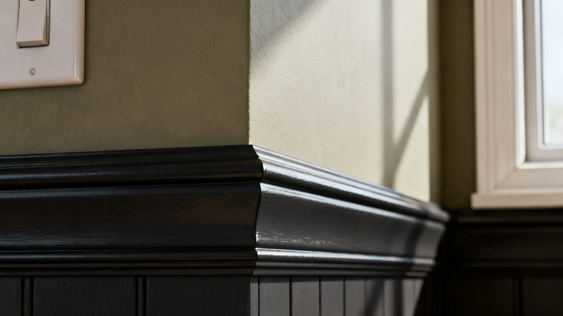 Close-up of charcoal trim beside a greige wall in a modern kitchen.