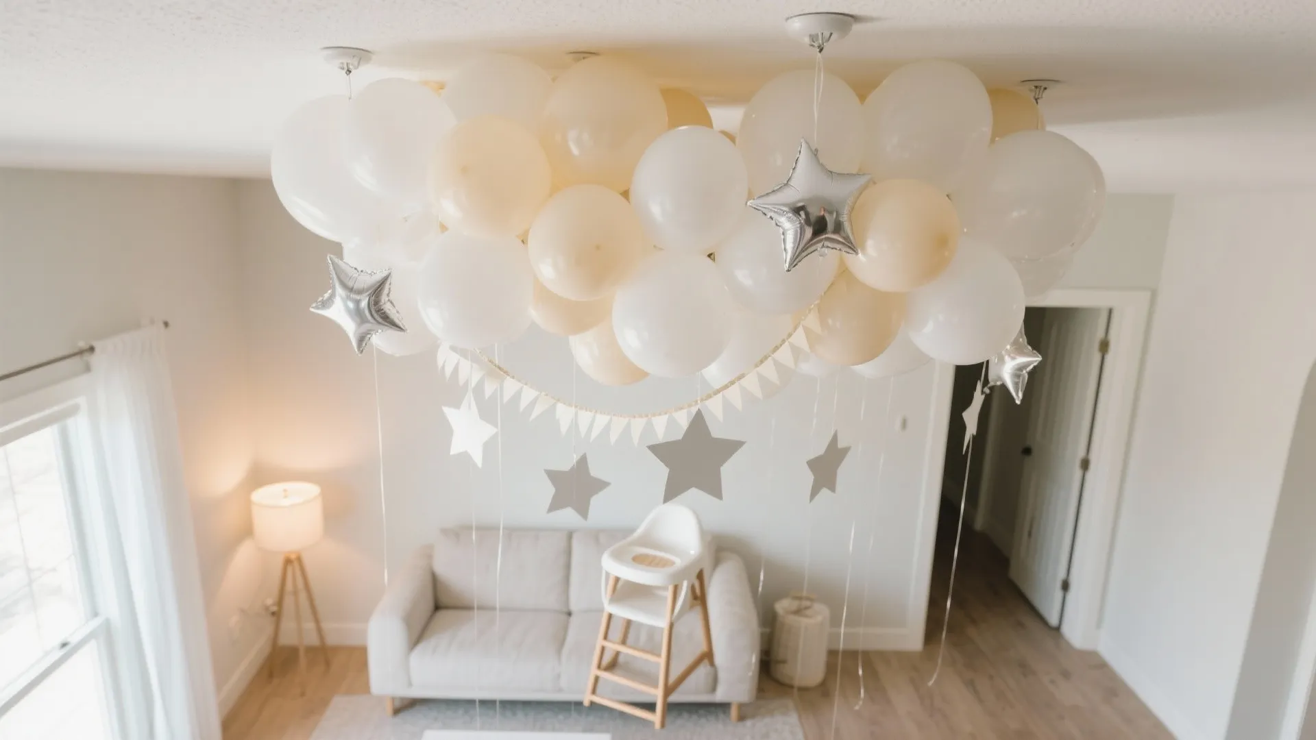 Living room ceiling decorated with white balloons silver stars a banner and small white sofa