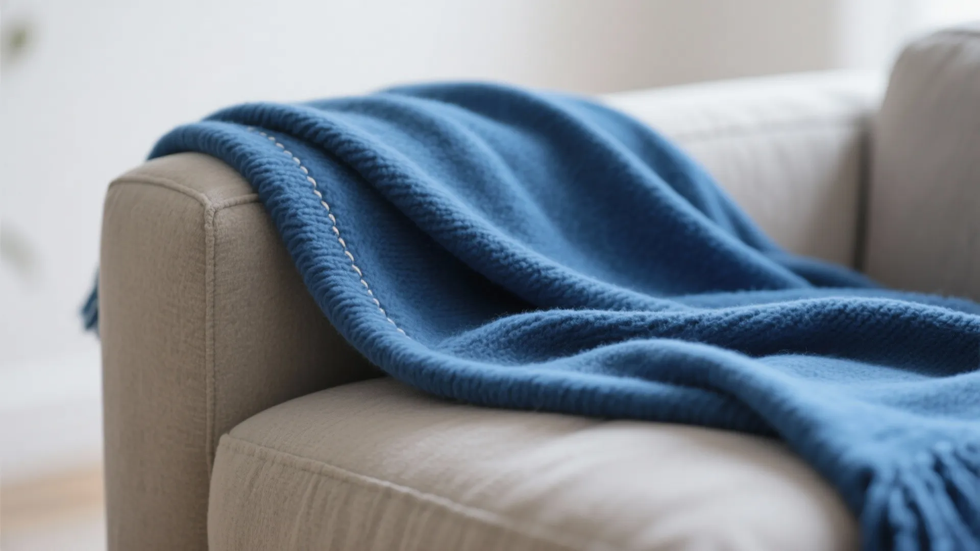 Macro of a cobalt throw layered over a greige cushion showing rich texture and stitching.