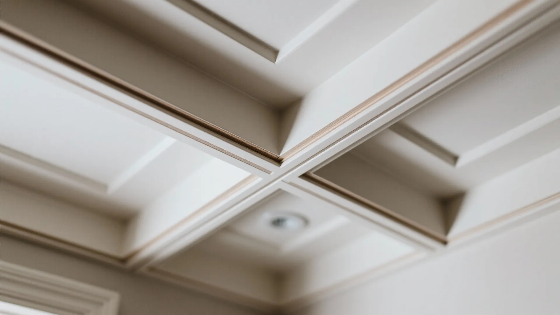 Macro of slim batten intersection on a shallow coffered gypsum ceiling with matte finish.