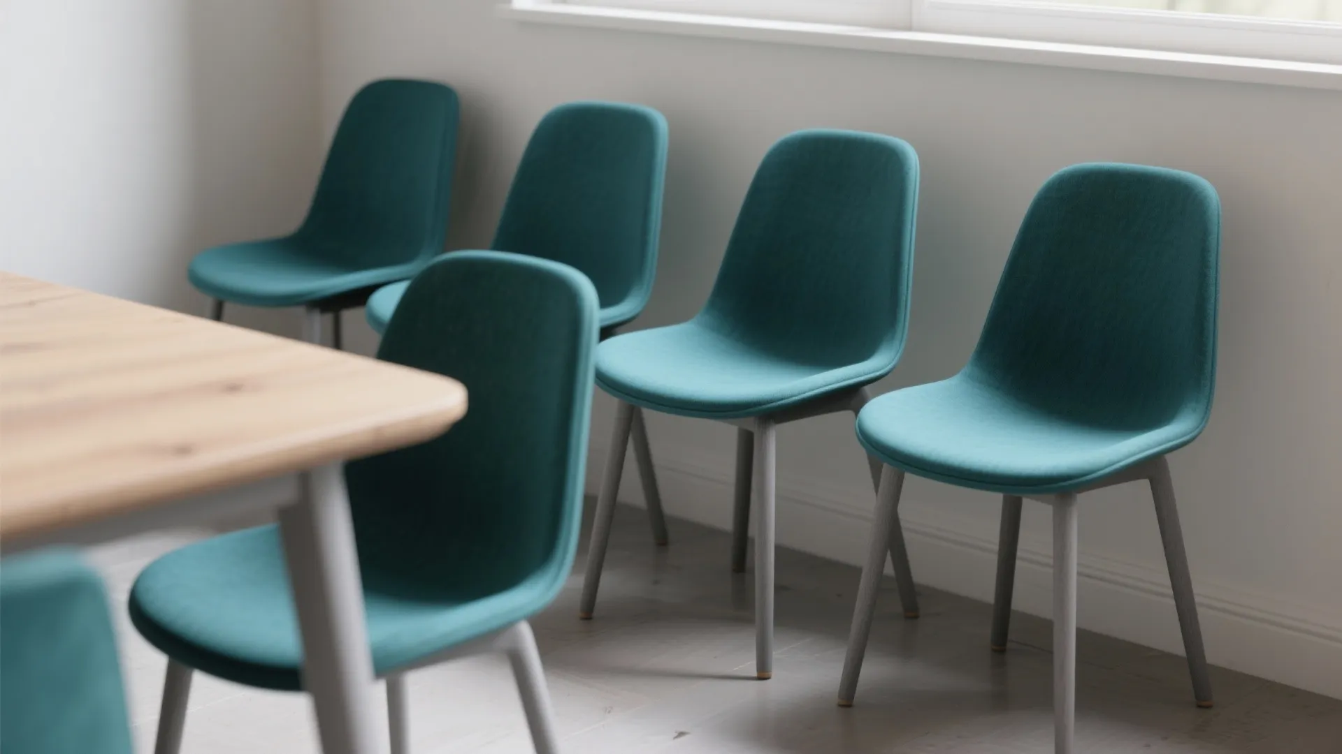 Four dining chairs with ash-gray legs and deep teal seats showing color-block paint contrast in a small dining nook.