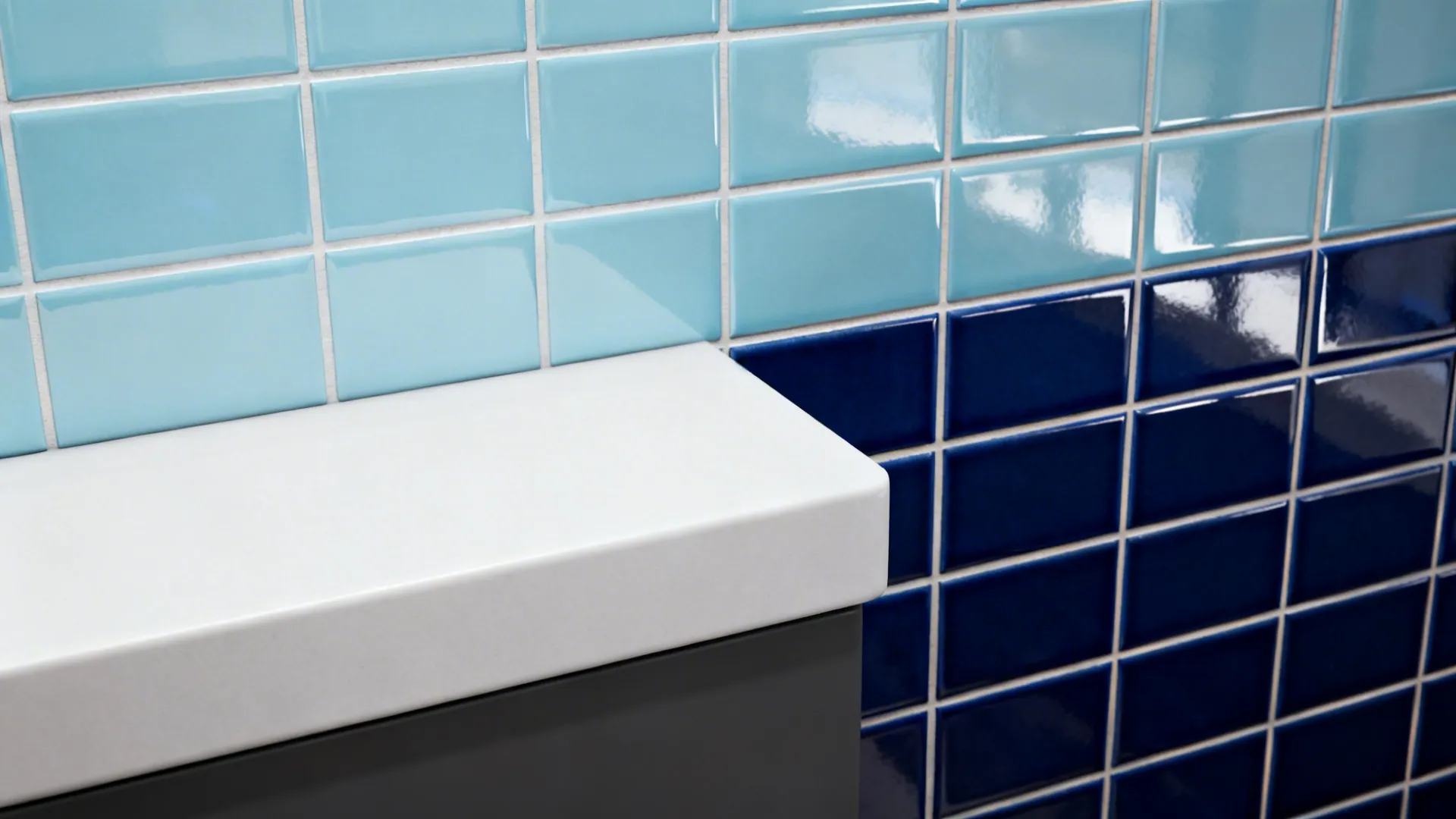 Macro of glossy pastel blue and deep navy tiles with neat grout at a counter edge.