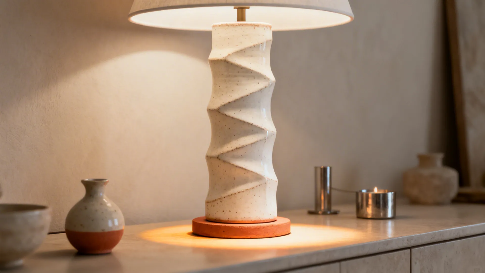 Tall columnar ceramic lamp with textured glaze on a console table