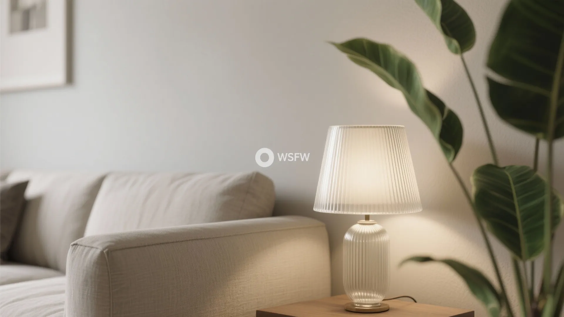 Macro detail of a greige wall, linen sofa, ribbed glass lamp, and green plant leaves creating a soothing, low-chroma scene.