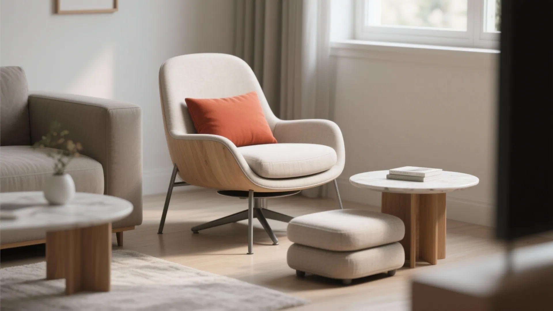 Modern beige armchair with orange pillow and footrest on wood floor next to marble table