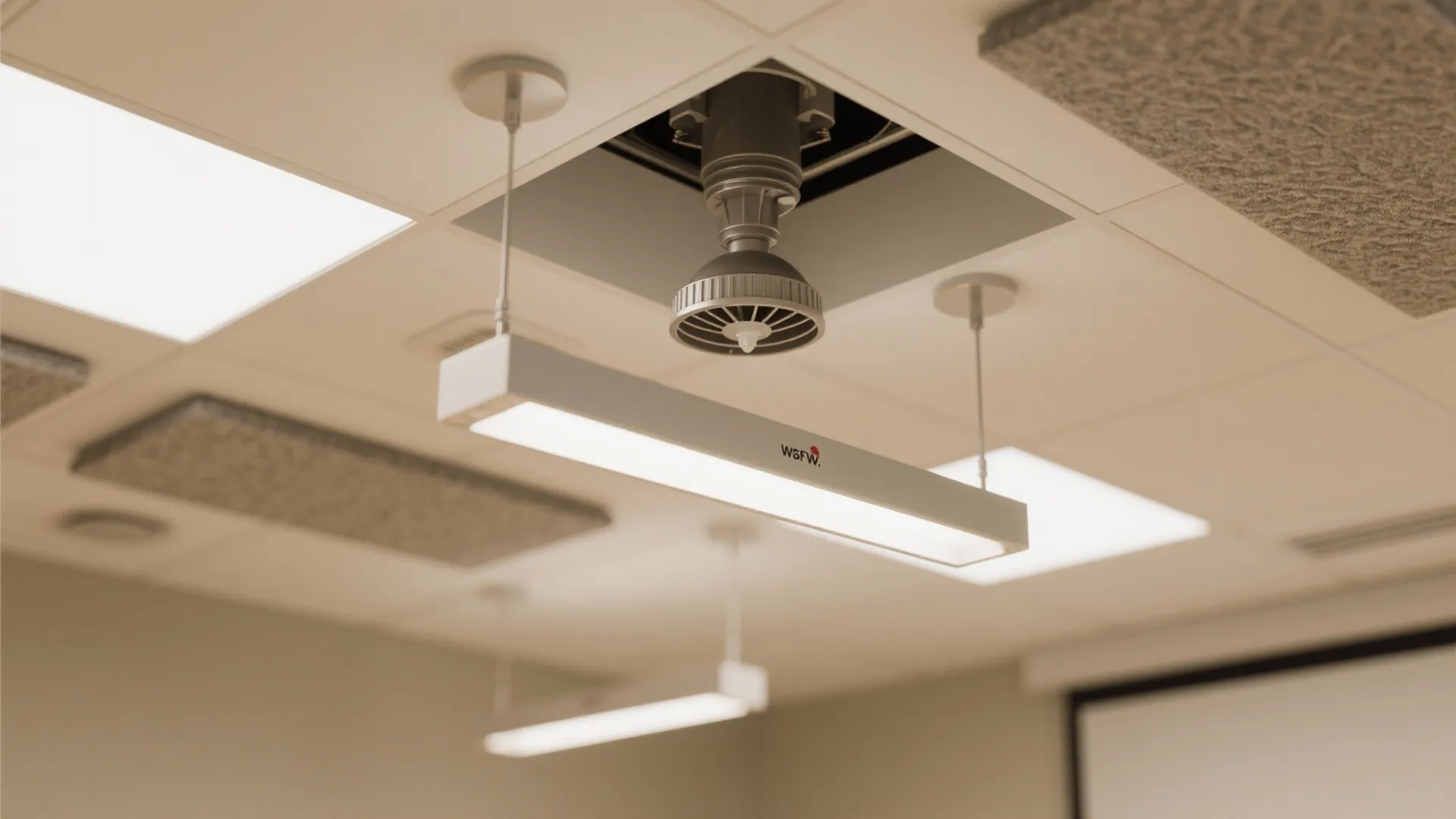 Close-up of a concealed pendent sprinkler near pendant lights and acoustic baffles showing careful clearance.