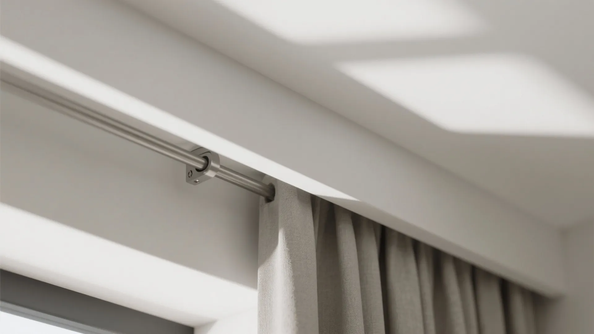 Close up of a metal curtain rod with grey fabric curtain hanging from a white ceiling