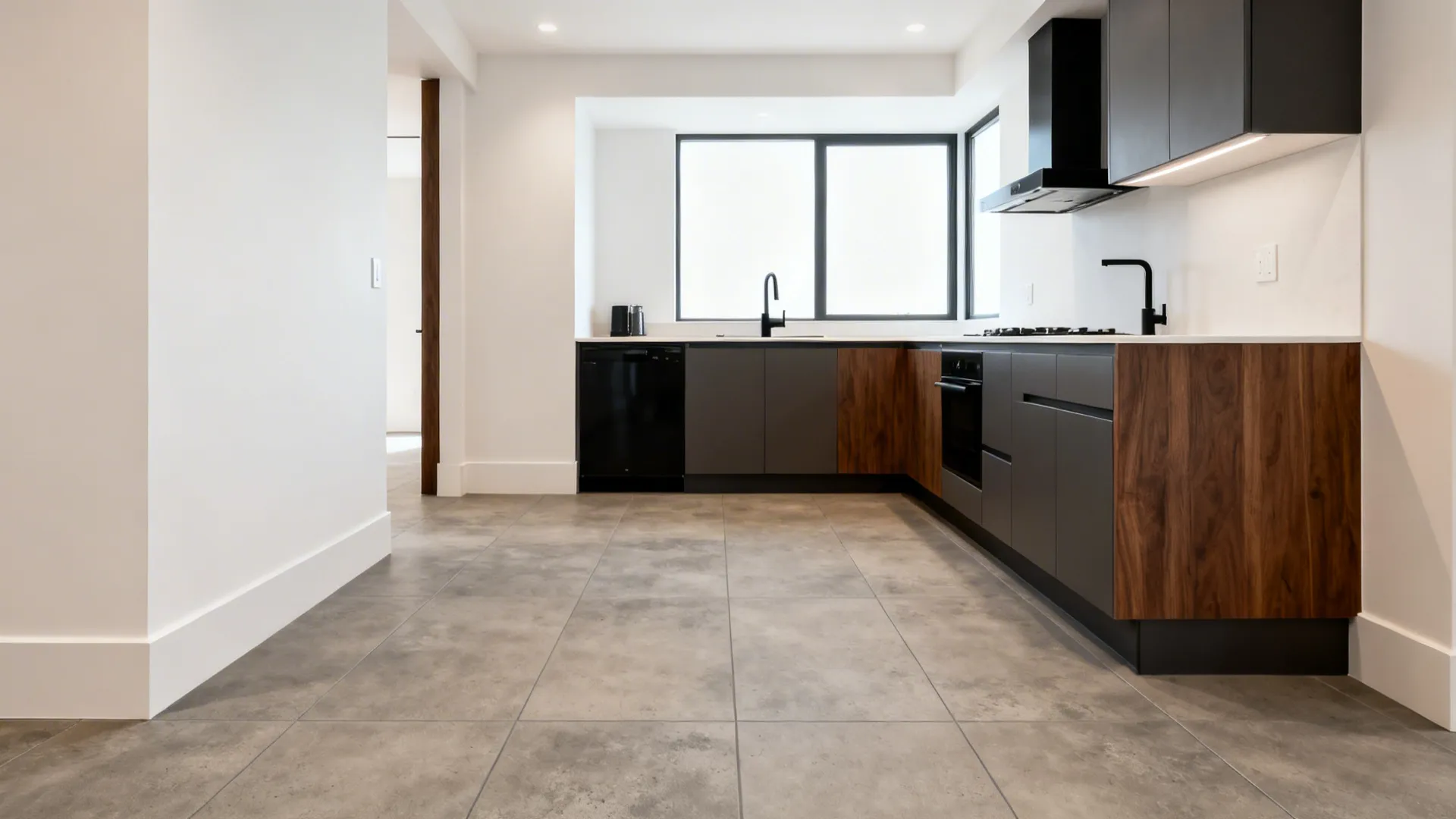 Modern L-shaped kitchen with warm mid-grey 24x48 concrete-look porcelain tiles and tight joints.