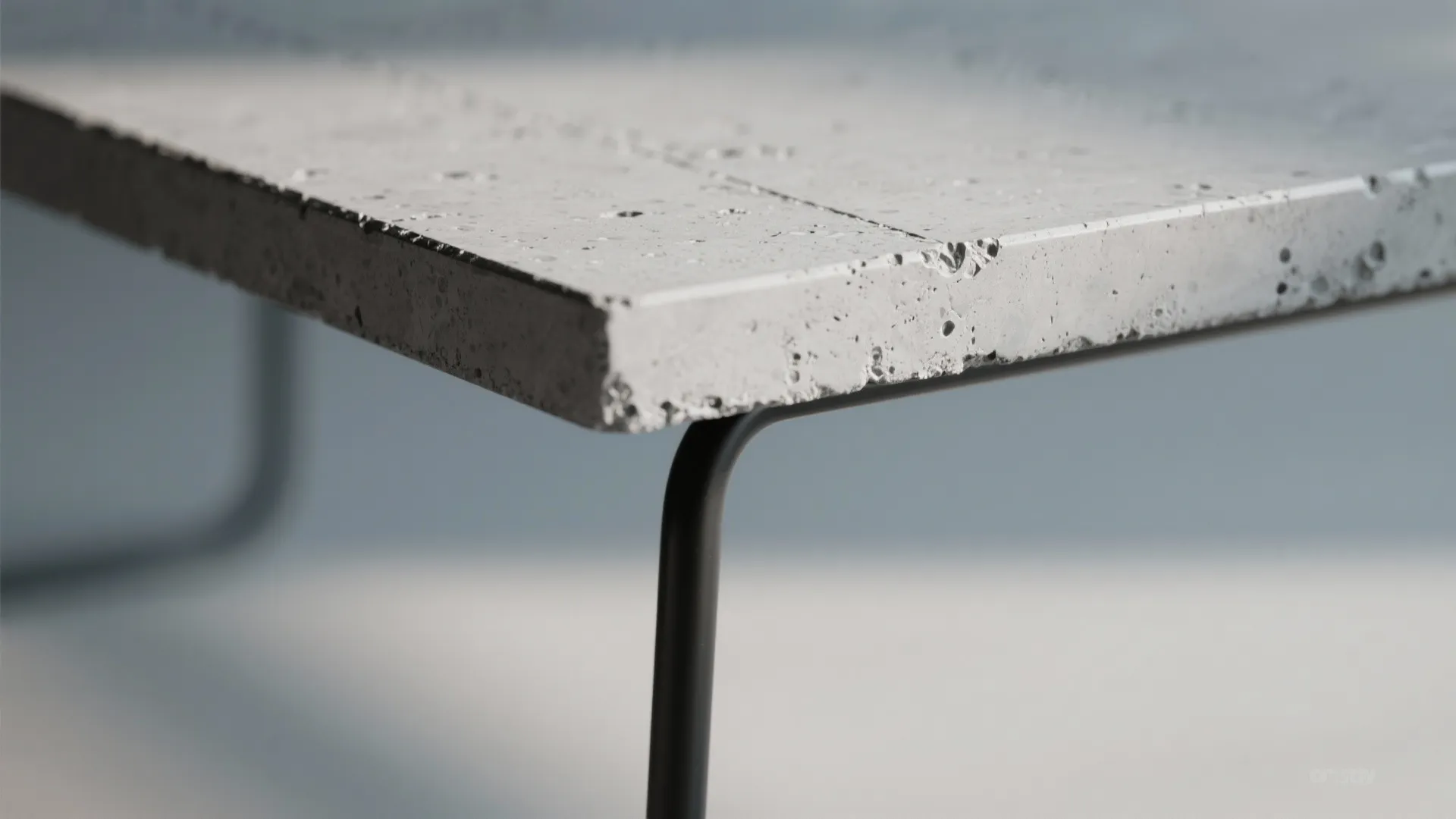 Macro view of a fiber-reinforced concrete tabletop edge with slim hairpin legs and textured finish.