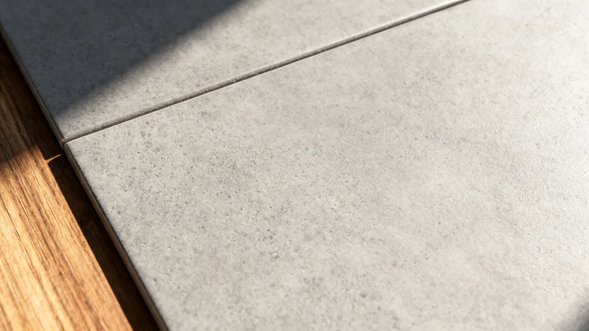 Macro of matte concrete-effect porcelain with tight grout joint and subtle texture.