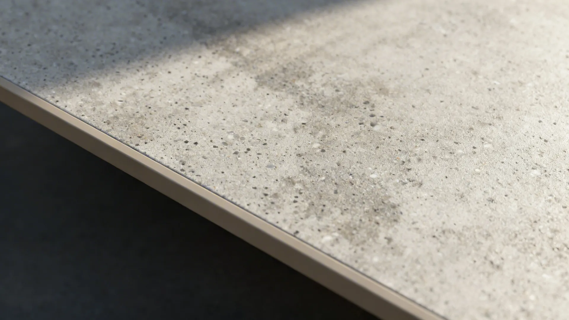 Macro of digital concrete laminate with mid-tone matched edge banding and subtle mottling.