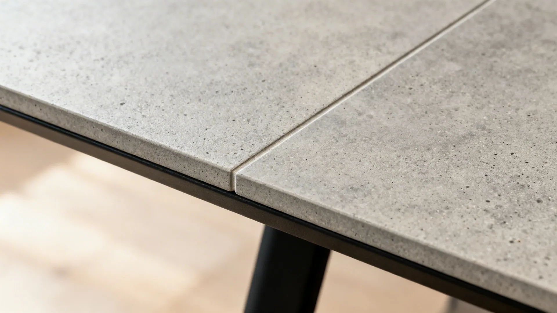 Macro of warm-gray concrete-look porcelain tile with minimal grout on a tabletop.