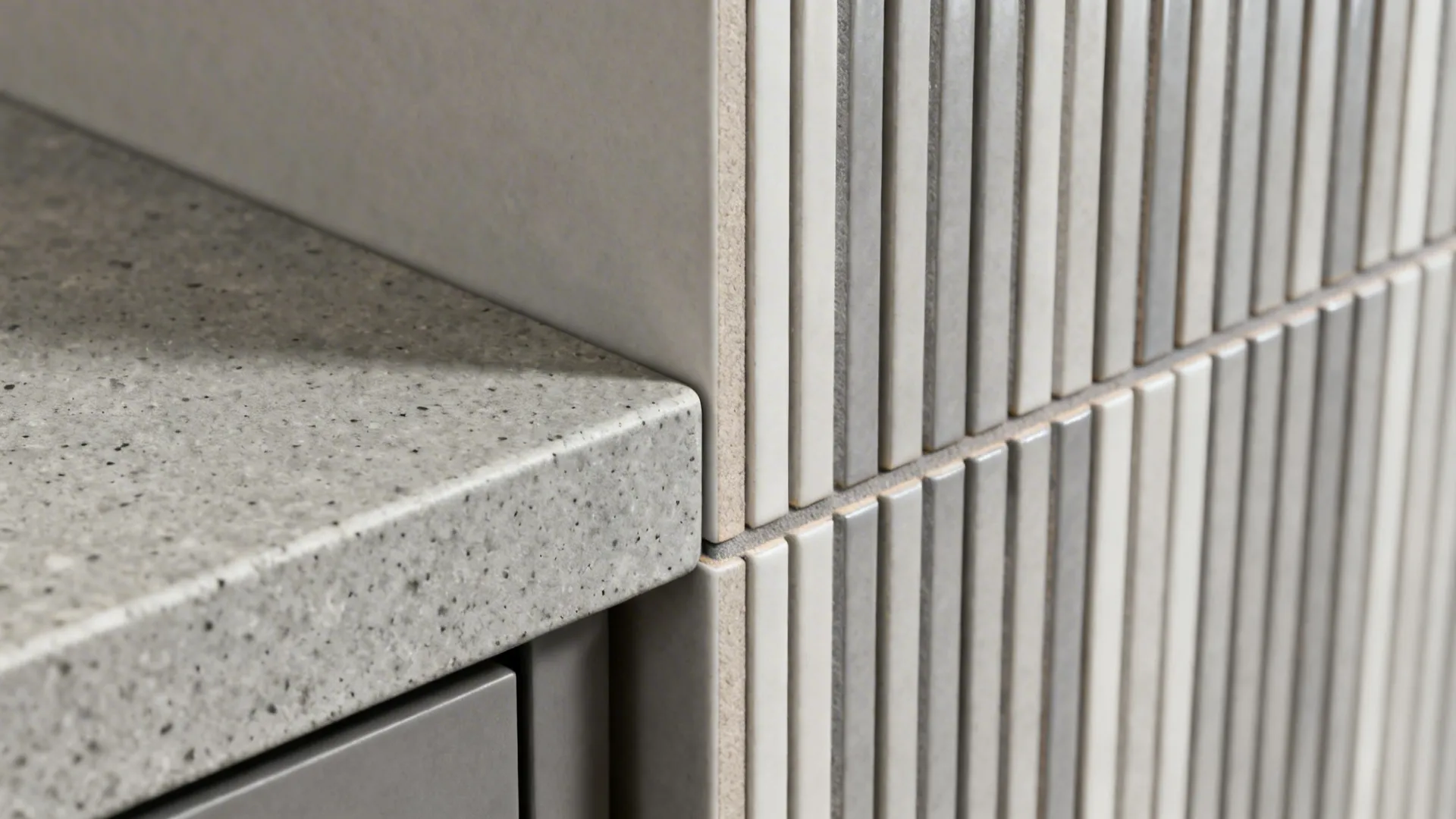 Macro of concrete-look quartz and skinny stacked tile with tight, color-matched grout.