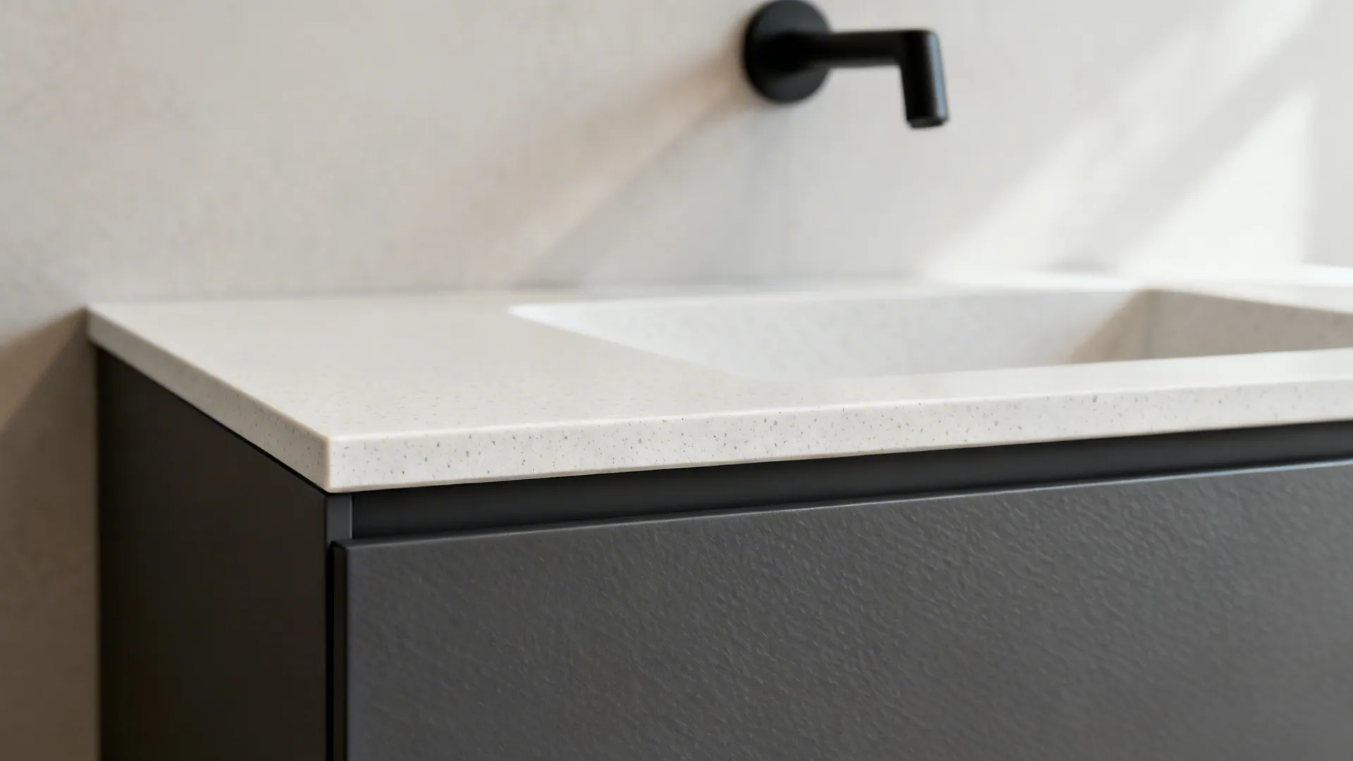 Macro detail of quartz basin edge, matte drawer front, and matte black spout.