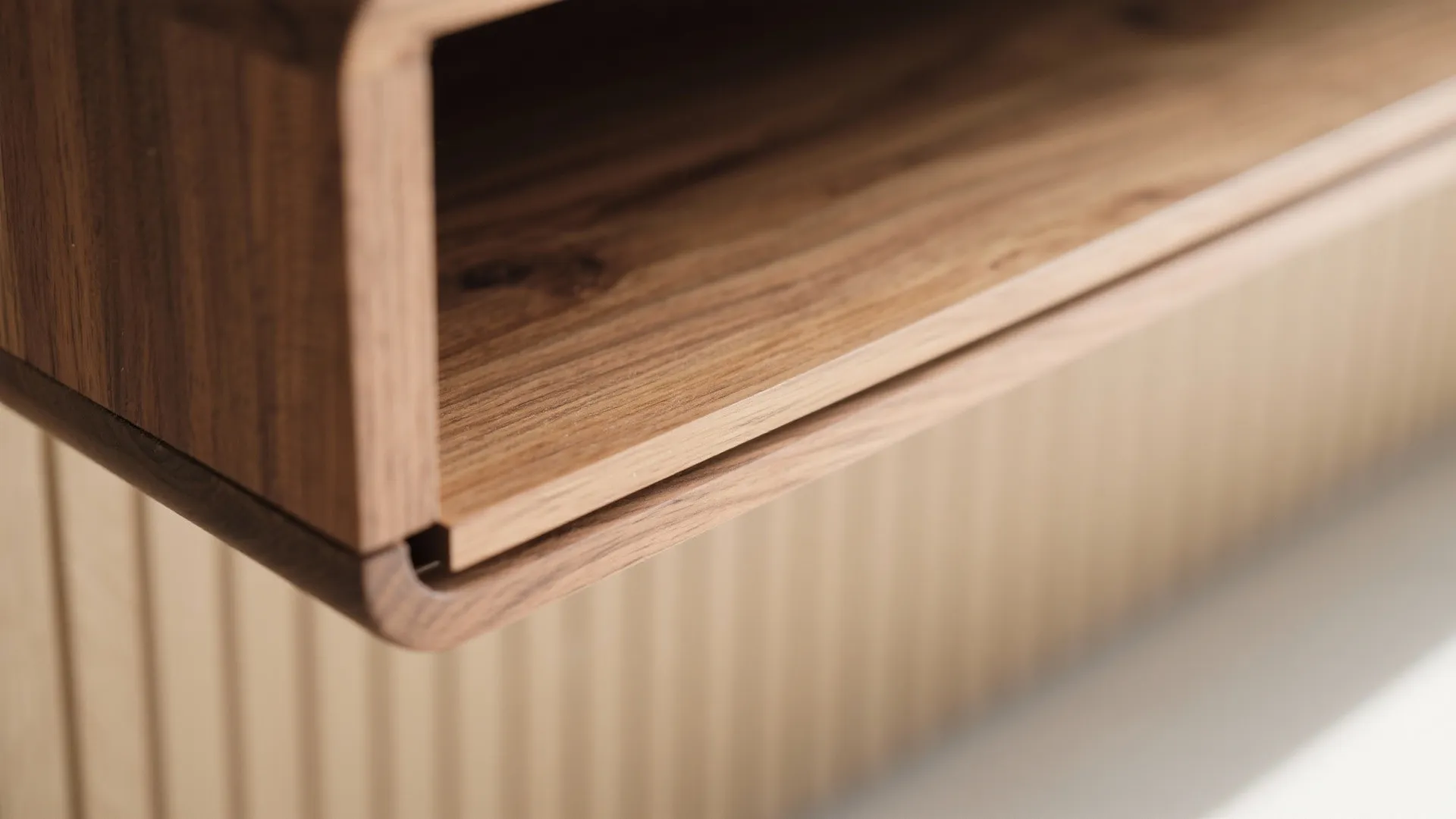 Close up of a wooden cabinet shelf showing clean edges wood grain and wall panel texture