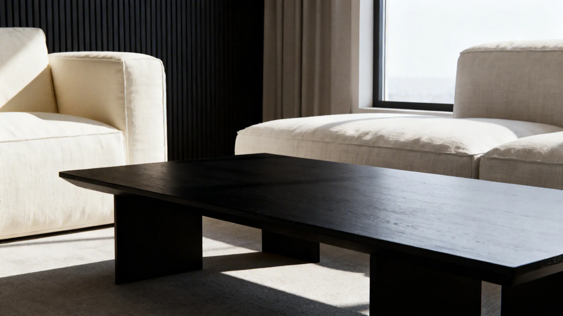 Black coffee table paired with pale linen sofas creating modern contrast