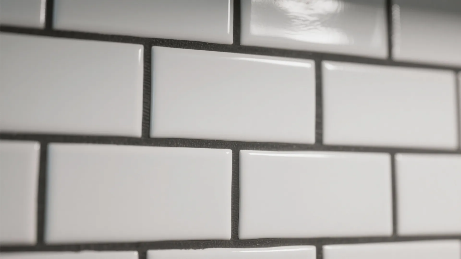 Close up view of white rectangular wall tiles with dark gray grout in brick layout