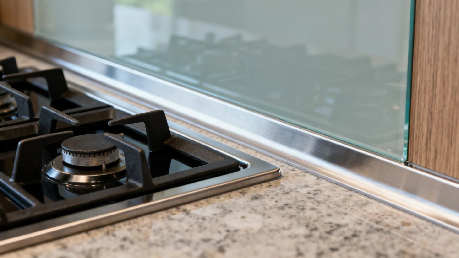Macro view of a cooktop with non-combustible upstand and tempered glass backsplash showing safe clearances.