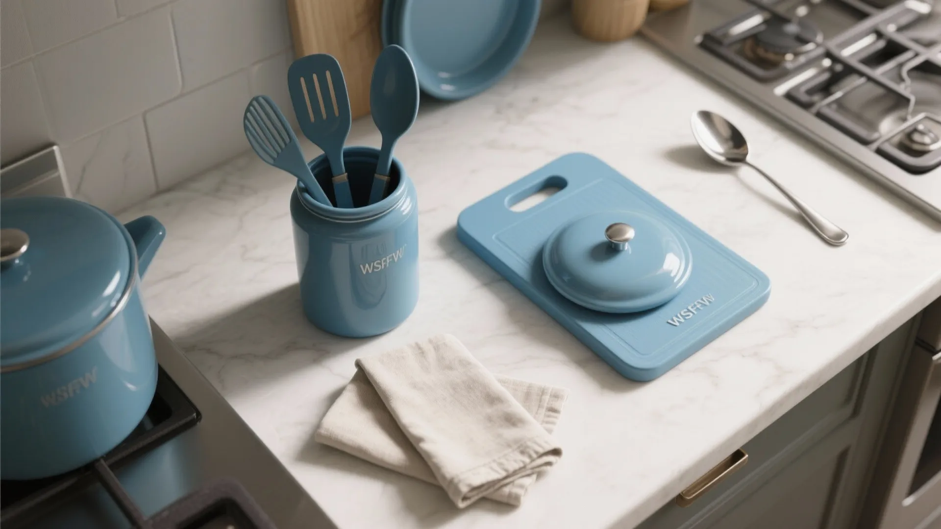 Blue kitchen tools including a pot cutting board and spoons on a white marble counter