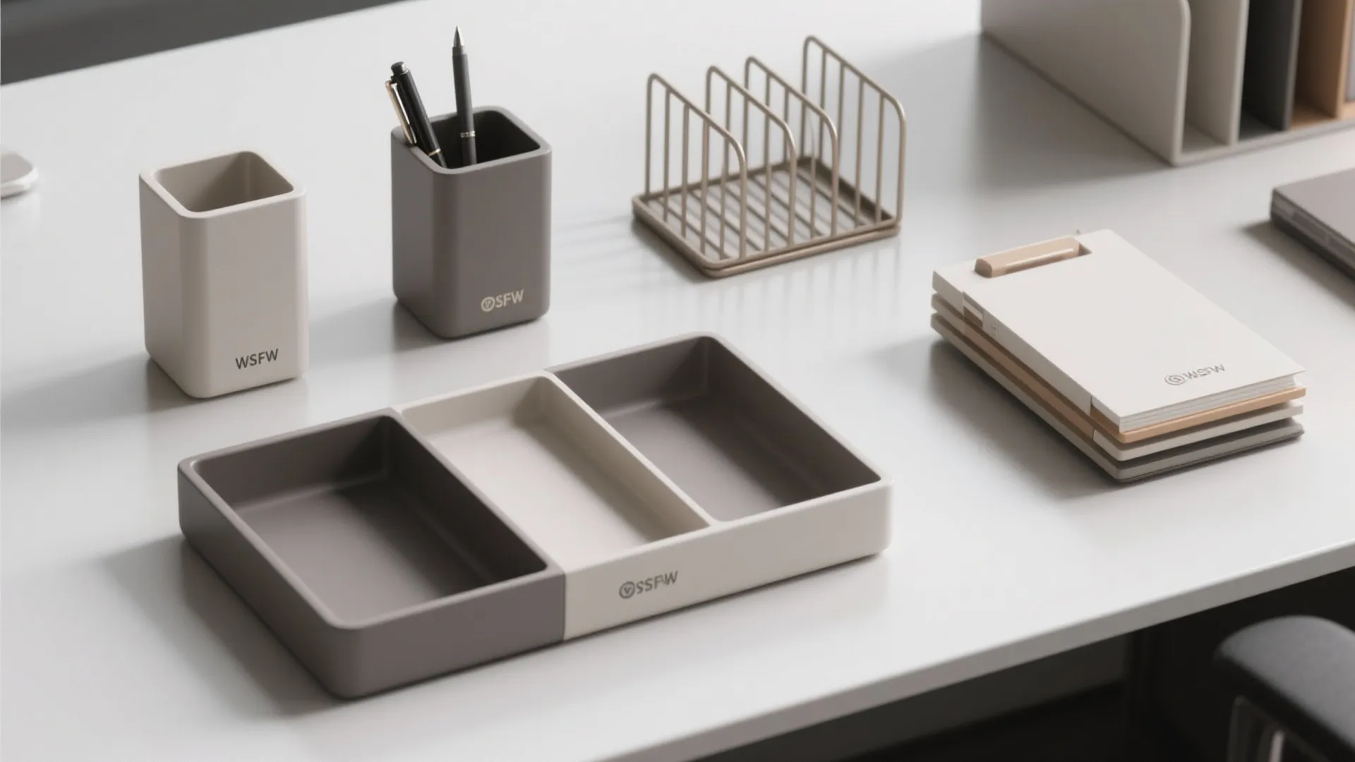 Neutral desk organizers including pen holders with pens and storage trays on a white desk