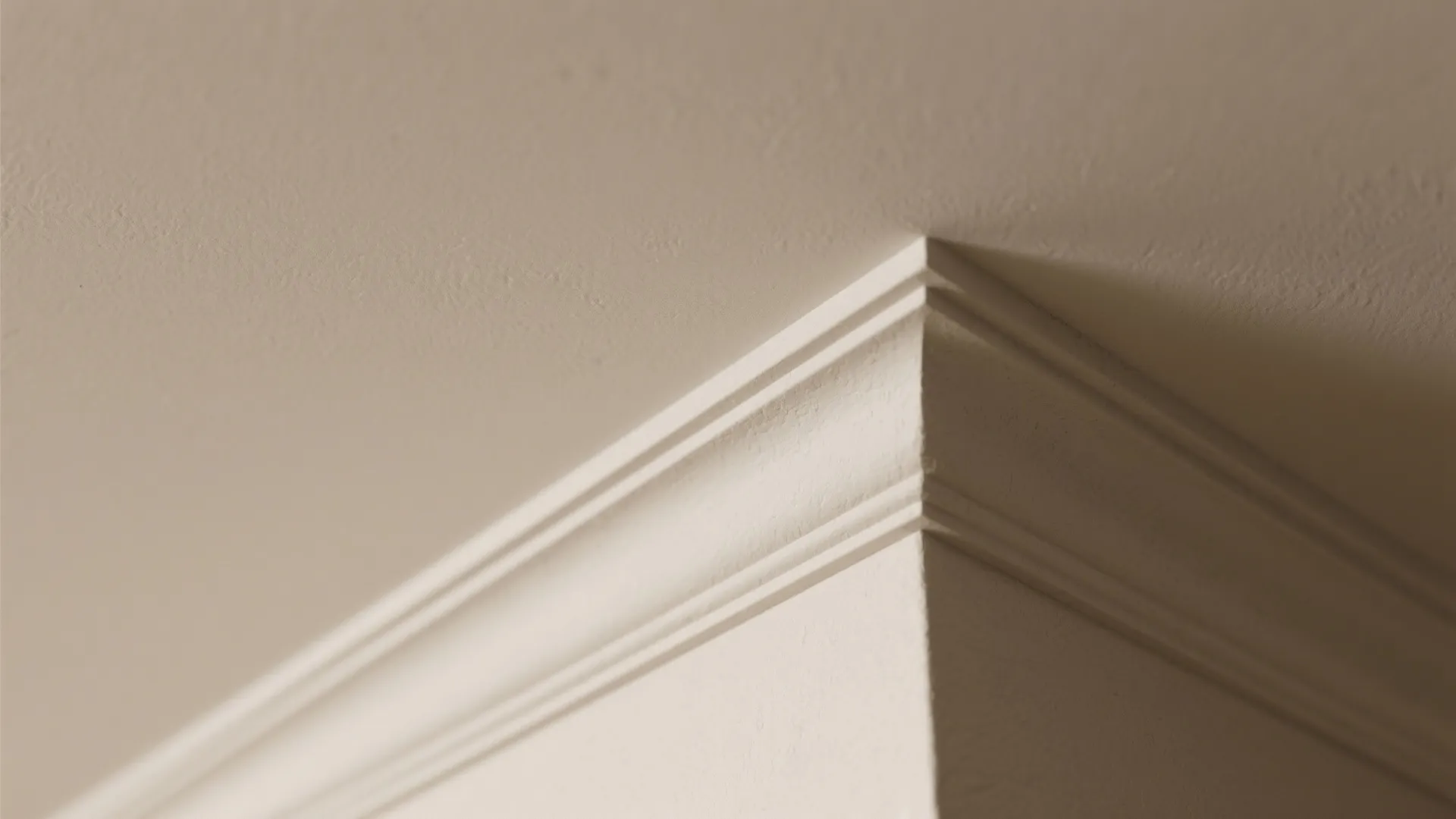 Close up of decorative white crown molding installed where the wall meets a flat ceiling