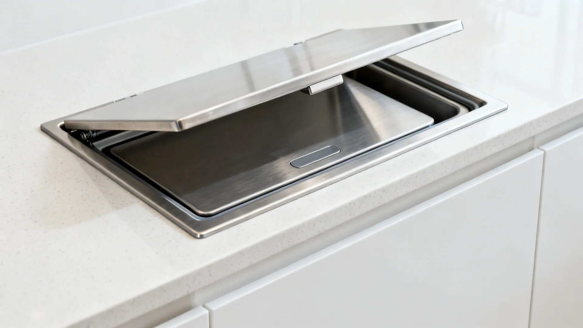 Flush stainless countertop hatch with silicone gasket over a hidden bin in a quartz counter.